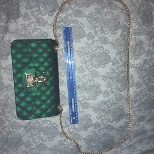 Emerald green thick clutch with yellow gold color chain strap and accents